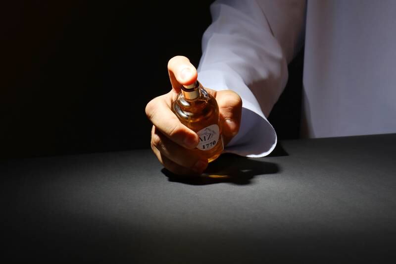 Braço masculino segurando frasco de perfume