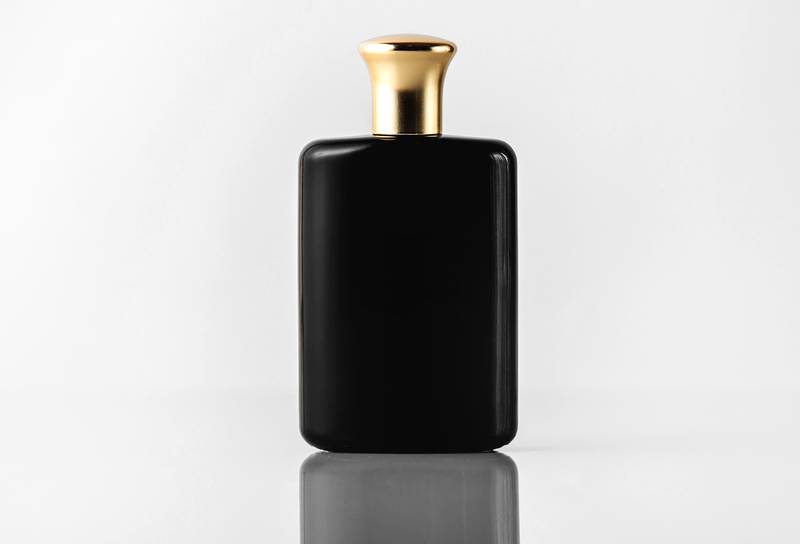 Frasco de perfume preto com tampa dourada em fundo branco
