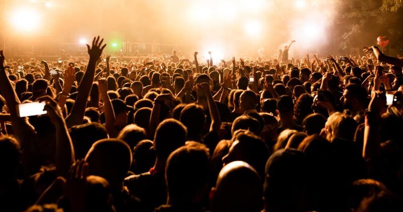 Vista trasera de un gran grupo de fanáticos de la música frente al escenario durante un concierto de música por la noche Copiar espacio